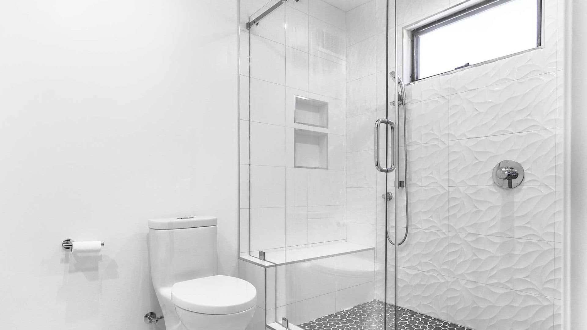 Renovated hall bathroom in the San Miguel neighborhood of Walnut Creek with a frameless glass walk-in shower, bench, and sculpted white tile