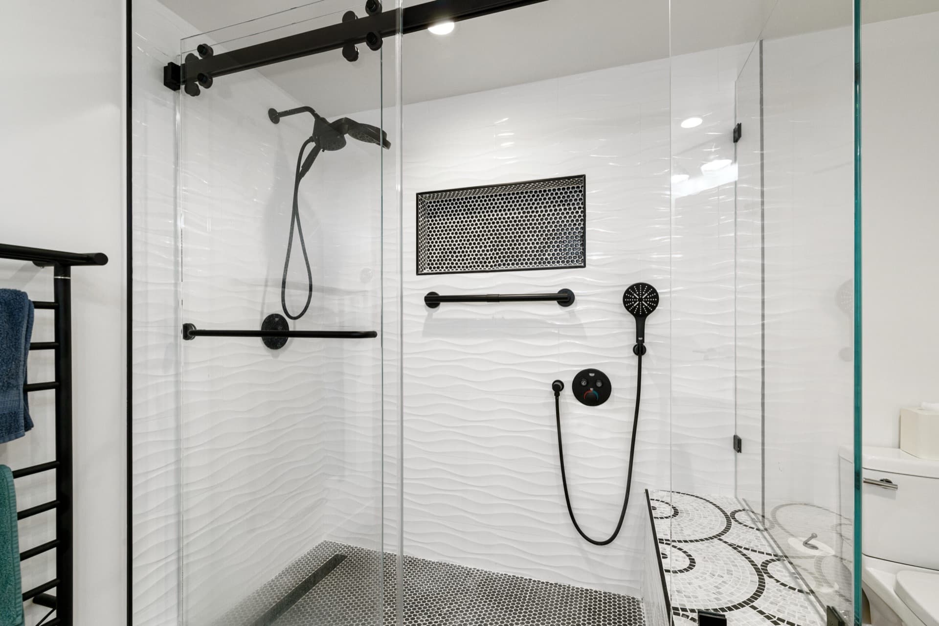 Remodeled walk-in shower with matte black fixtures and mosaic bench by a Renovation Bridge contractor