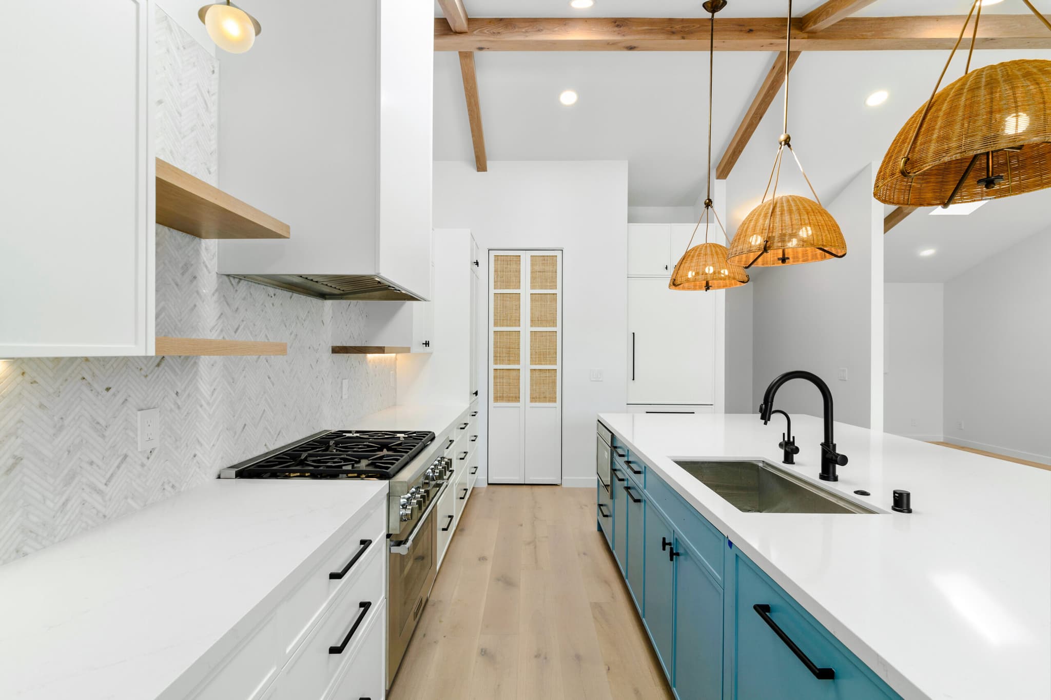 Kitchen island with waterfall quartz counter and full-height pantry cabinets
